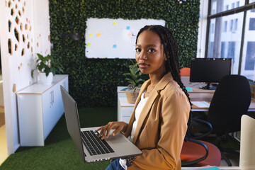 Happy african american casual businesswoman using laptop in office