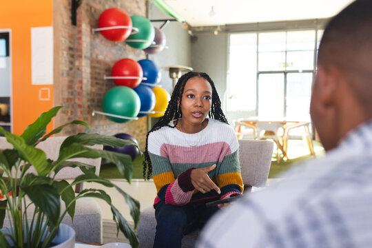Diverse female and male colleagues in discussion using tablet in casual office meeting