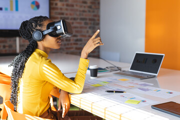 African american casual businesswoman using vr headset in office