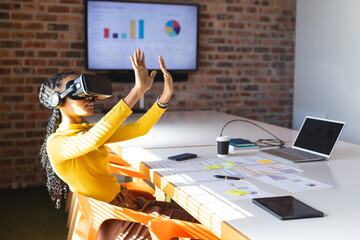 African american casual businesswoman using vr headset in office