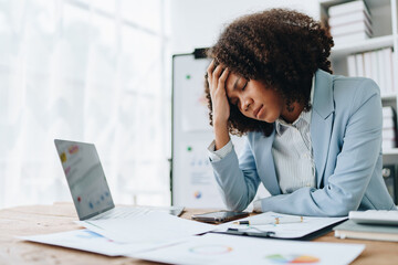 Burnout American African business woman in stress works with many paperwork document, migraine...