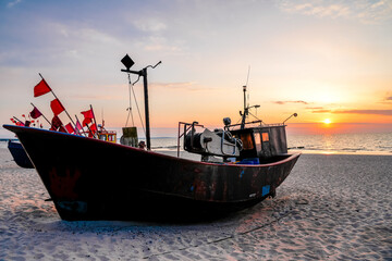 Sunset on the beach on the Polish Baltic Sea. Fishing boat in the evening near Międzyzdroje,...