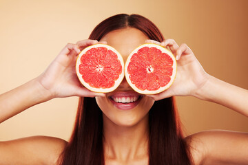 Beauty, grapefruit and a woman with skin care in studio for natural dermatology, cosmetics or wellness. Facial, fruit and healthy diet for detox or nutrition of model person on a brown background