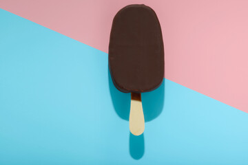 covered chocolate popsicle  with ice cream and hard shadow on blue, pink background, creative decoration of minimal summer concept