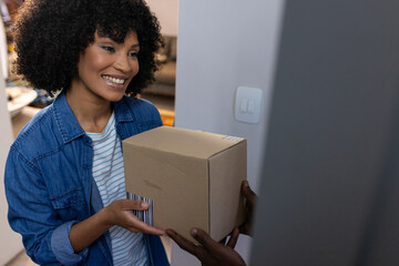 Happy biracial woman receiving parcel at home