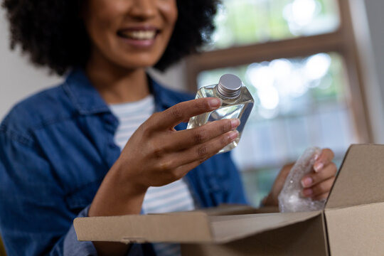 Happy biracial woman unpacking parcel at home