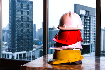 Close up stack of colorful safety working helmets put on table in office