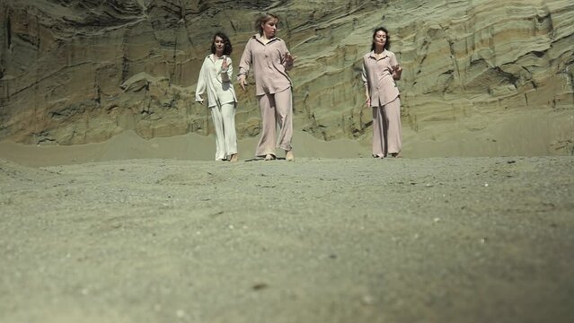 three Caucasian women in casual clothes are dancing. dance rehearsal. three women in the desert. slow motion video. High quality Full HD video recording
