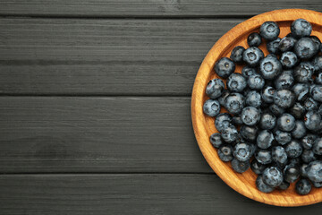 Fresh blueberry in wooden bowl on black background. Concept of healthy and dieting eating