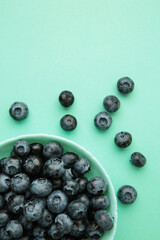 Fresh blueberry in bowl on mint background. Space for text. Concept of healthy and dieting eating