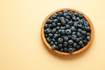 Fresh blueberry in wooden bowl on beige background. Top view. Concept of healthy and dieting eating
