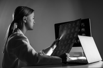 A young female doctor looks at an MRI image of a human head. Black and white photo