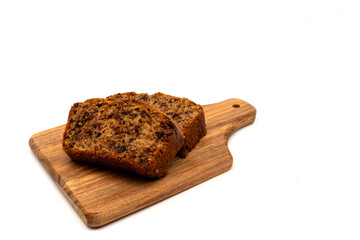 Slices of freshly baked homemade chocolate banana bread on a wooden board. Isolated on white background with copy space.