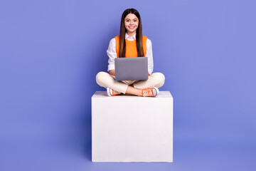 Full body photo of nice cheerful girl sit podium cube use wireless netbook isolated on violet color...