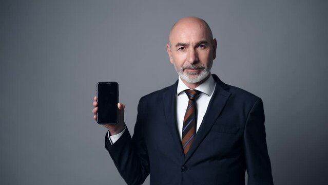 Middle-aged white man in a suit smiling with a smart phone.