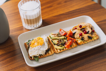 Breakfast toasts with different toppings with a cup of coffee.