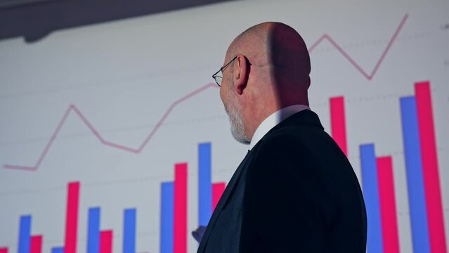 A middle-aged Caucasian business person giving a presentation using a projector screen.