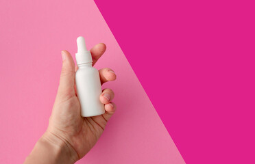 Layout of a glass bottle in the hands of a woman. Tank of white color with cosmetic product, serum....