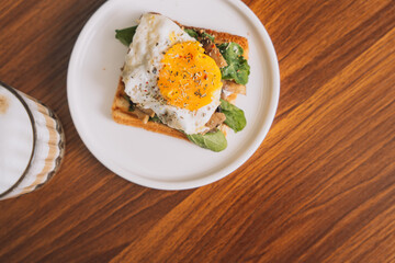 Toast with scrambled eggs and lettuce on a white plate with coffee.