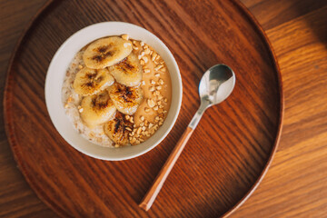 Oatmeal with banana slices in a white cup with a spoon.