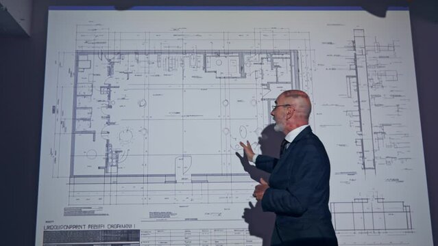 A middle-aged Caucasian business person giving a presentation using a projector screen.