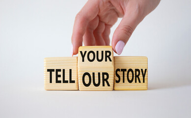 Tell Your or Our story symbol. Businessman hand turns wooden cubes and changes the words Tell Our story to Tell Your story. Beautiful white background. Business concept. Copy space