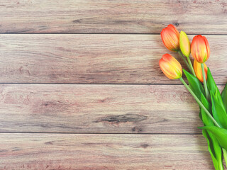 flat lay of yellow red  tulip flowers on wooden table background with copy space for text. Feminine concept.