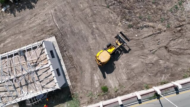 Yellow tractor and workers working on construction