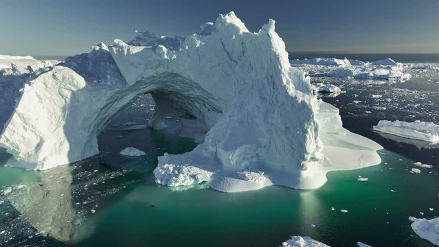 Gaint iceberg with ice cave melting in the ocean. Icebergs from melting glacier float in Disco Bay, near Ilulissat, Greenland. Aerial shot, climate change concept