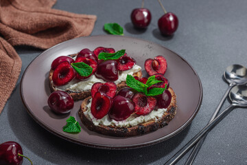 Fresh bread sandwiches with sweet cherry, cream cheese and mint leaves. Morning breakfast concept