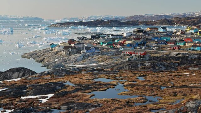 Village with colorful houses - Ilulissat, Greenland. Panning shot of arctic settlement above Arctic Circle against the backdrop of glaciers and icebergs. Nature of Greenland