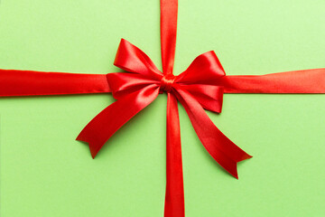 Top view of Red ribbon rolled and red bow isolated on colored background. Flat lay with copy space