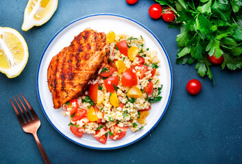 Grilled chicken with bulgur tabbouleh salad with tomatoes, parsley and olive oil and lemon dressing, blue stone table background, top view - obrazy, fototapety, plakaty