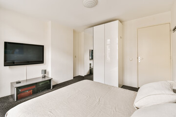 a bedroom with a flat screen tv on the wall and white bedding in front of the television is mounted