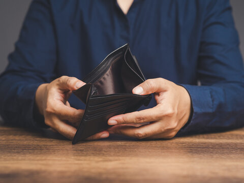 Close-up of hands opening an empty wallet while sitting at the table