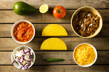 Directly above shot of tortillas with cheese, meat, avocado, lemon, tomato, sauce, cabbage and chili