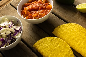 Foto op Aluminium High angle view of cabbages with red sauce in bowls and tortillas on wooden table © vectorfusionart