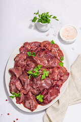 Raw chicken liver on stone background. Fresh ingredients ready for cooking, parsley, red pepper