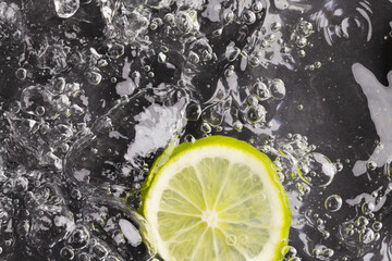 Close up of lime slice in water with copy space on black background