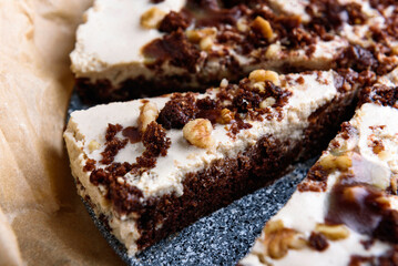 Homemade brownie chocolate cake with coffee cream and walnuts on baking paper.