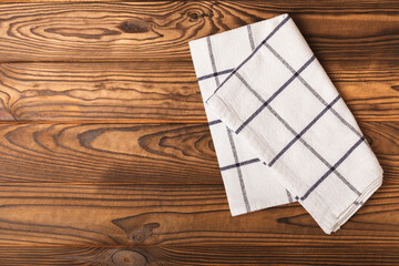 Kitchen towel on a brown wooden background. Kitchen utensils and textile napkin. A stack of cotton towels on the table. Home decor. Tablecloth for the table. Copy space for text. Mockup for design.