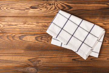 Kitchen towel on a brown wooden background. Kitchen utensils and textile napkin. A stack of cotton towels on the table. Home decor. Tablecloth for the table. Copy space for text. Mockup for design.