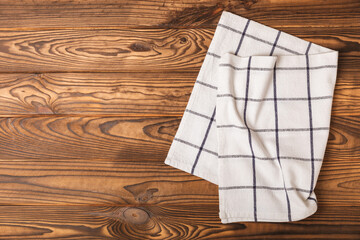 Kitchen towel on a brown wooden background. Kitchen utensils and textile napkin. A stack of cotton towels on the table. Home decor. Tablecloth for the table. Copy space for text. Mockup for design.