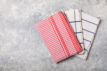 Kitchen towel on a light textured background. Kitchen utensils and textile napkin. A stack of cotton towels on the table. Home decor. Tablecloth for the table. Copy space for text. Mockup for design.