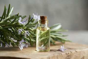 A bottle of aromatherapy essential oil with fresh rosemary leaves and flowers - obrazy, fototapety, plakaty