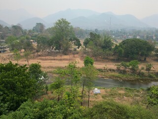 The landscape of Pai in Thailand taken from above with the drone with trees, a river and in the background the mountains.