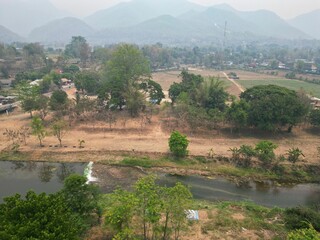 The landscape of Pai in Thailand taken from above with the drone with trees, a river and in the background the mountains.