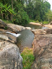The Mo Pang Waterfall in Pai, Thailand, surrounded by rocks and trees taken from above with the drone.