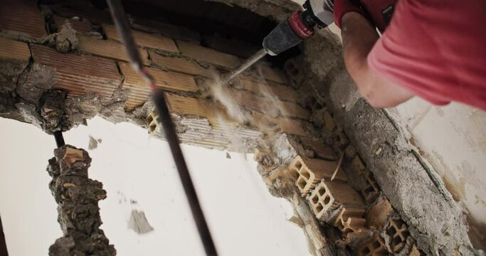 The builder dismantles the wall with a perforator. A professional is engaged in repairs in the building. High quality 4k footage