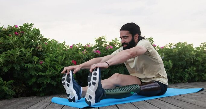 Young fit man with prosthetic leg doing stretching exercise outdoor - Disabily and sport concept